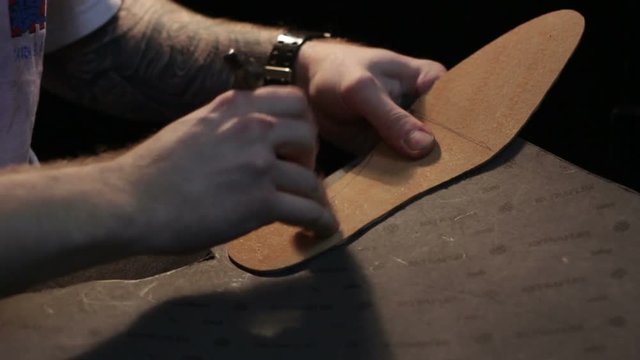 Shoemaker sews shoes, hammering sole