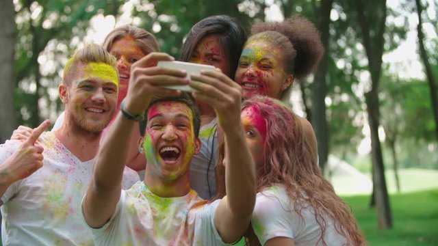 cheerful company of young friends having fun in the Park with the colors of Holi make a selfie