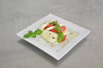 Caprese salad with tomatoes, basil and mozzarella on the table of stainless steel