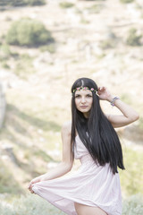 Woman with very long black hair wear flower headpiece and pink dress pose outside in nature