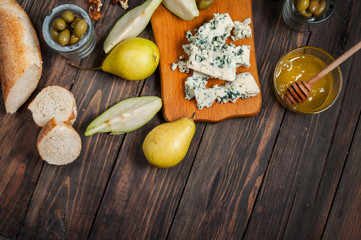Blue cheese with honey, olive and pears on rustic table