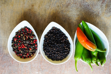 closeup green chilli peppers and different types of peppercorns
