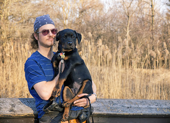 Young man holding rottweiler puppy