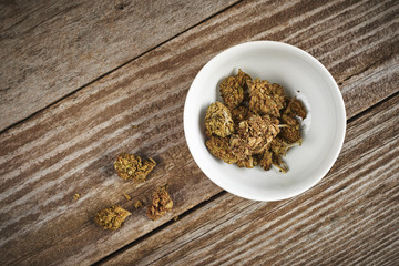 a bowl of medical marijuana on a wood surface