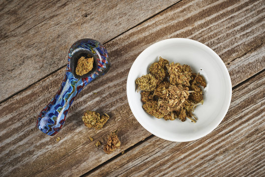 a pipe and bowl with medical marijuana on a wood surface