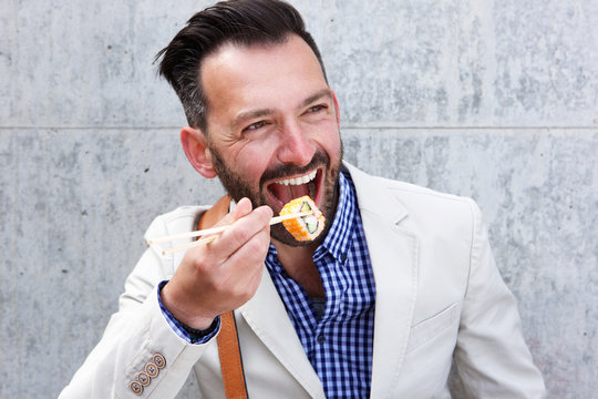 Happy Mature Man Eating Sushi