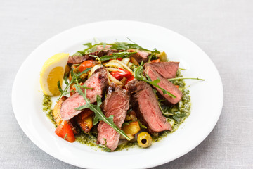 Roast beef with arugula, vegetables and lemon sliced, lies on th