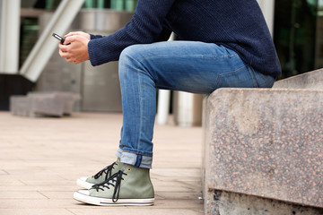 Man sitting outdoors by the street and using cellphone