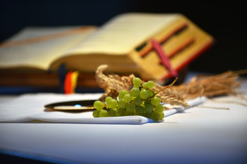 Grapes on a paten and open prayer book in the background .