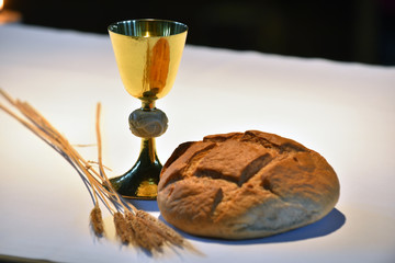 Elegant golden chalice and a loaf of bread on the altar..