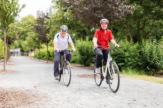Smiling Senior Couple Cycling In Park