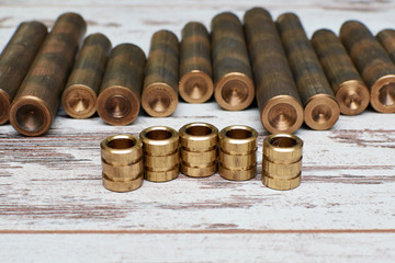 bronze rods and finished parts of type sleeve with grooves on white shabby background