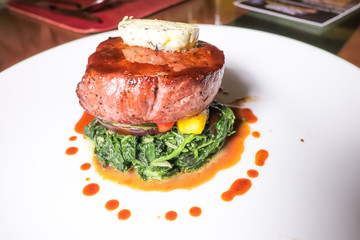 Beef steak served with spinach and topped with sauce