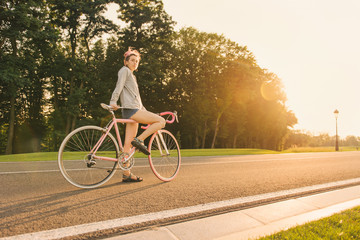 Woman on pink colorful bicycle with dreadlocks starting