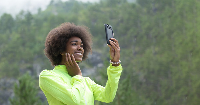 Beautiful afro american woman taking photos outdoors in a forest