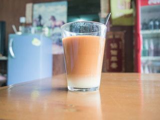 Hot tea cup with milk on wooden table in asian cafe