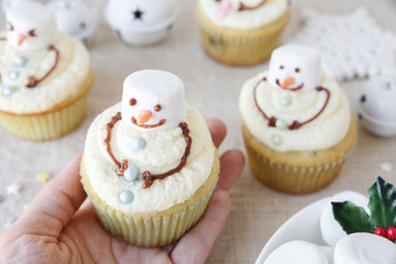 hand holding fun homemade melting snowman Christmas cupcakes for kids