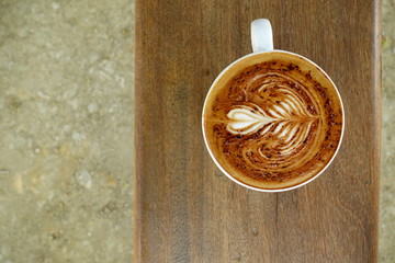 cup of latte art coffee on wooden background