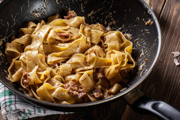 Pappardelle pasta with prosciutto and cheese sauce on pan