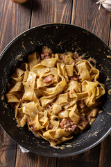 Pappardelle pasta with prosciutto and cheese sauce on pan