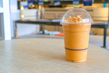 Thai milk tea spin with ice in plastic glass on wooden table.