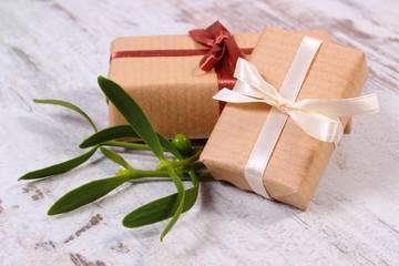 Wrapped gift for Christmas and mistletoe on old wooden background