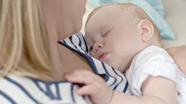 Blond tightly sleeping toddler lying on his mother chest on nap time
