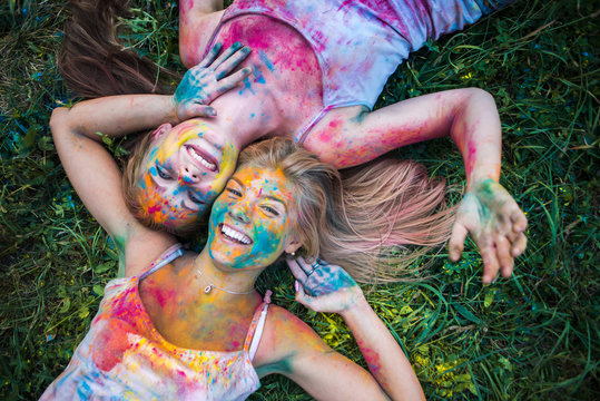 girls celebrate Indian holi festival with colorful paint powder on faces and body