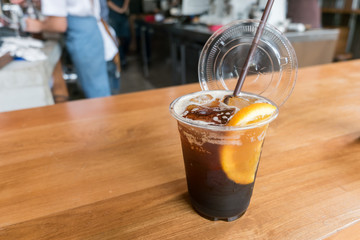 Glass of iced cold brew coffee with orange tonic and slice of orange on wooden table