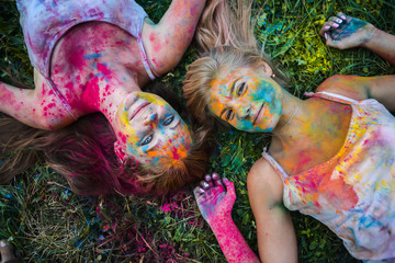 girls celebrate Indian holi festival with colorful paint powder on faces and body