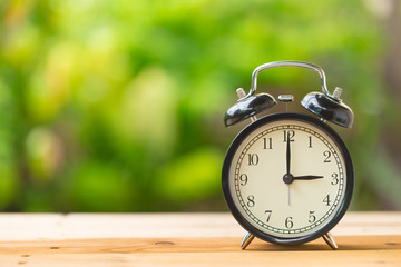 clock on wood table in the green garden time at 3 o'clock