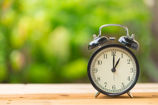 clock on wood table in the green garden time at 1 o'clock