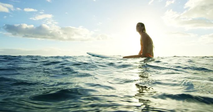Beautiful surfer girl enjoying sunset surf