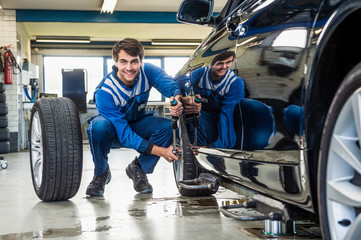 Confident Mechanic Changing Car Tire In Garage