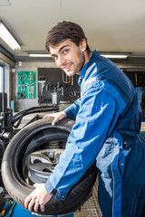 Fototapeta na wymiar Confident Mechanic Mounting Car Tire On Rim In Garage