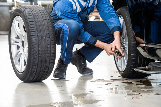 Male Mechanic Changing Car Tire In Garage