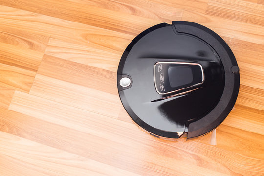 Robotic vacuum cleaner on wood parquet floor, Smart vacuum, new automate technology housework.