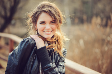 Naklejka premium autumn outdoor portrait of young beautiful woman with natural makeup in leather jacket and plaid shirt, soft vintage toned