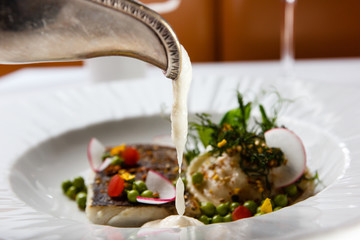 High French cuisine. Grilled fish with vegetables and foam sauce