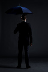 Businessman with a blue umbrella in a studio