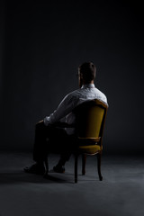 Businessman sitting in an armchair on a dark background