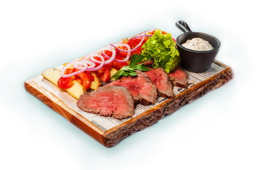 Beef with potatoes and greens on a wooden tray.