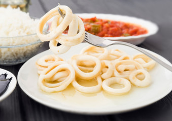 fork picking squid rings a plate on black