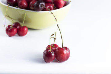 cutlery red cherries on white table and in the background a bowl with cherries
