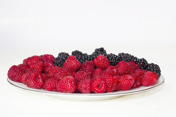 Fresh raspberries and blackberries on plate isolated on white background