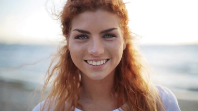 happy young redhead woman face on beach