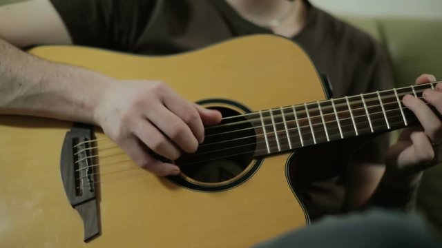 Young man's hands playing the acoustic guitar.