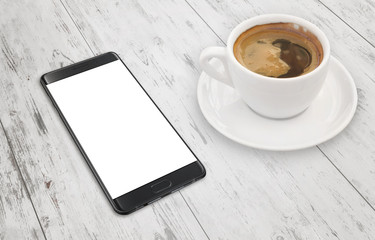 Modern black smart phone on white wooden table with blank display for mockup. Coffee beside.