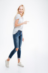 Full length portrait of a casual woman pointing finger away