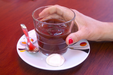 Woman taking a glass with coffee and ice cubes